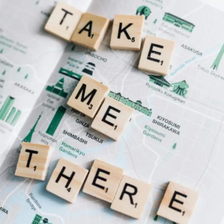 Scrabble tiles spelling 'Take Me There' on a map convey a clear way to reach your aspirations.